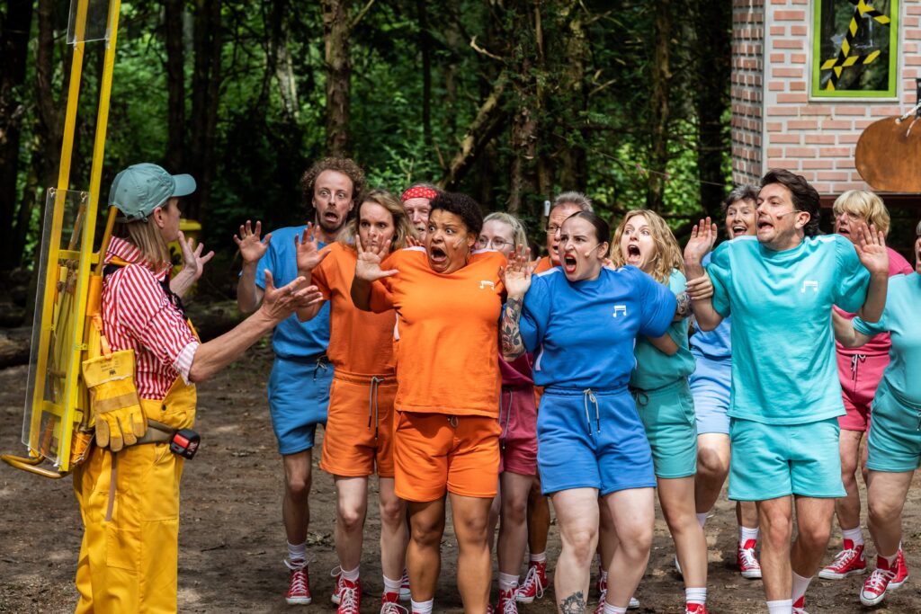 Spelers kijken geschokt terwijl de speler in gele tuinbroek hen aanspreekt.