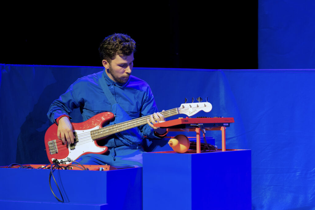 Een speler zit en speelt op zijn rood/witte elektrisch gitaar