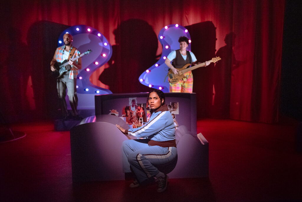 Twee muzikanten en een speler op een paars met rood podium