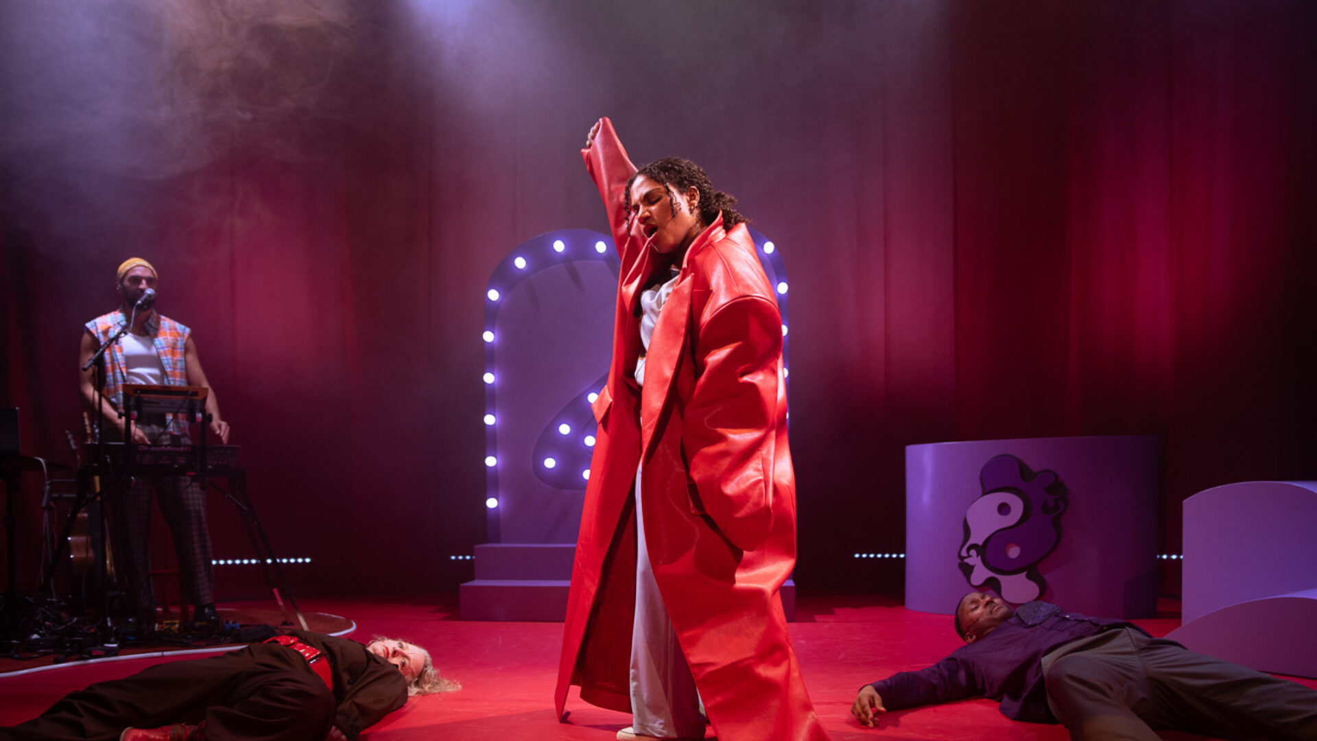 Nia met een rode, leren, grote jas aan op een paars rood podium