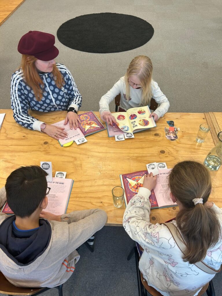 Kinderen die aan tafel een boek lezen.