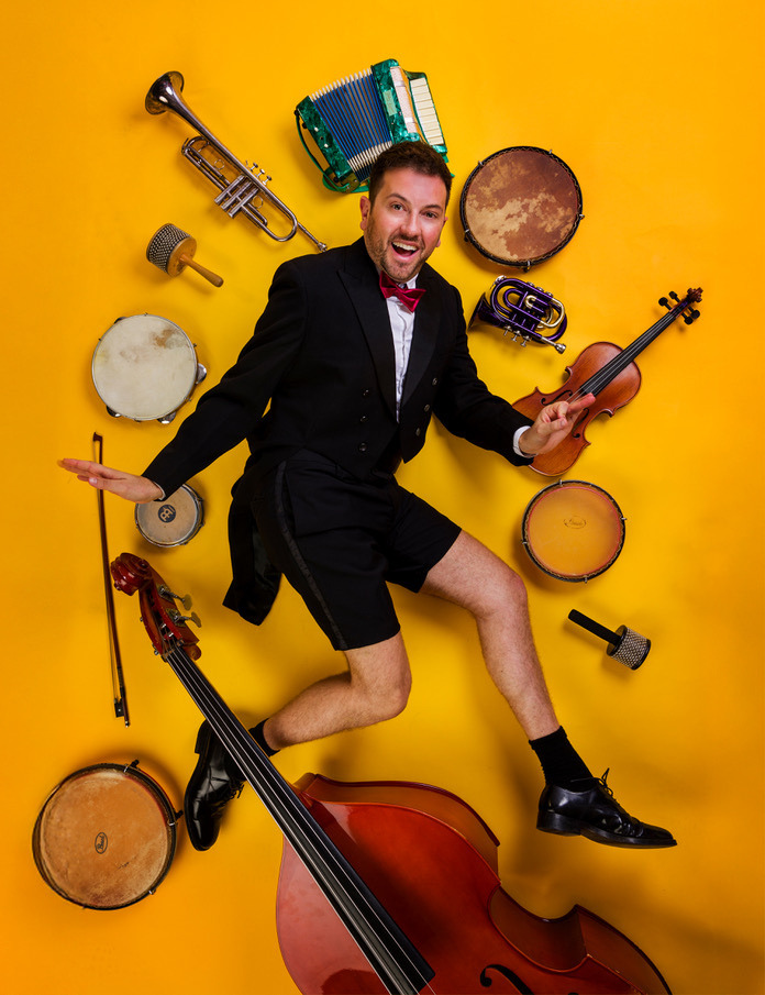 Een man die omringt is door verschillende muziekinstrumenten